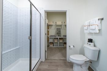a bathroom with a white toilet and a shower with a glass door
